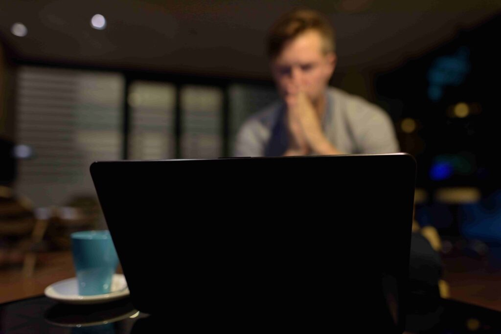 Concerned Young Man Using a Laptop in the Living Room